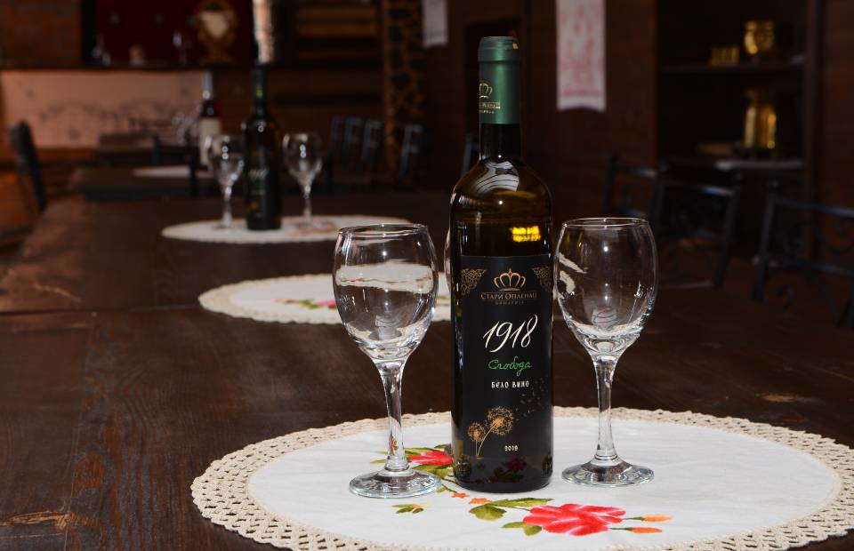 Slika flaše belog vina i dve vinske čaše na stolu